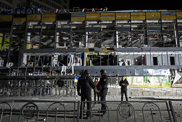 Ukrainian law enforcement officers stand next to a destroyed supermarket building following a missile attack in Kharkiv early on Monday (AFP photo)