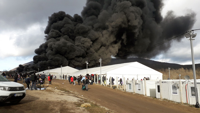 Refugees leave a camp as a fire burns, near the north-western village of Lipa, Bihac region, on Wednesday (AFP photo)