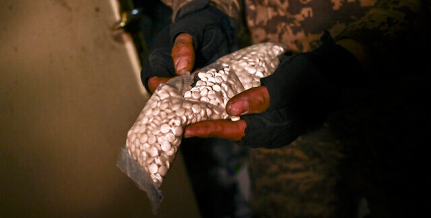 A Syrian rebel fighter holds a bag containing pills of captagon found at Mazzeh Military Airport in the west of Damascus on December 12, 2024  (AFP photo)