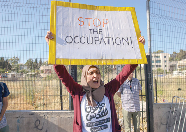A woman holds up a sign reading in English 'stop the occupation' as Palestinian, Israeli, and foreign activists gather for a demonstration against Israeli occupation and settlement activity in the Palestinian territories and East Jerusalem, in Jerusalem's Palestinian Sheikh Jarrah neighbourhood, on Friday (AFP photo)