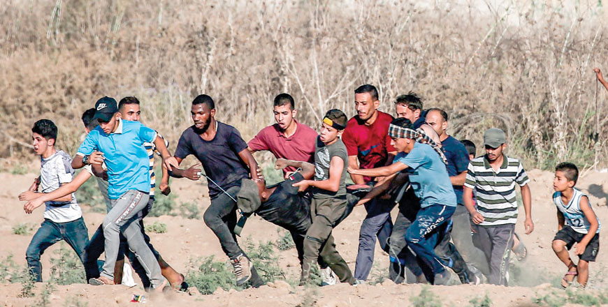 Palestinian protesters carry away a man injured during confrontations following a demonstration along the border with Israel east of Bureij in the central Gaza Strip on Friday (AFP photo)
