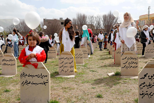   Iraqi-Kurds visit a grave site in Halabja near the monument for victims of the Halabja gas massacre that killed some 5,000 people as they mark the 31th anniversary of the attack on Saturday (AFP photo)