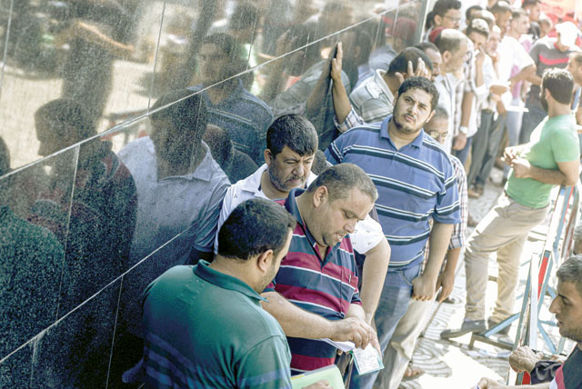 Palestinians stand in a queue outside the post office to receive Qatari cash aid, in Gaza City, on Monday (AFP photo)