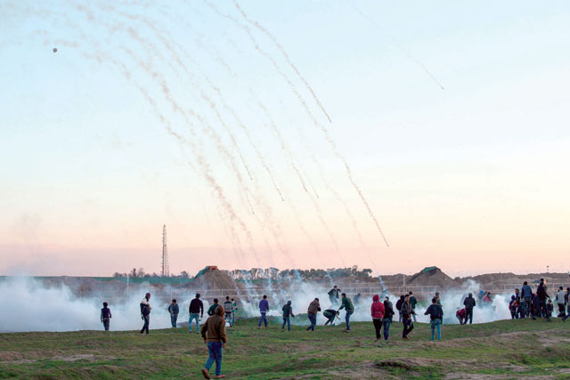 Tear gas canisters falling amidst Palestinian protesters during clashes with Israeli forces across the border fence, following a demonstration along the border with Israel east of Gaza City on Friday (AFP photo)