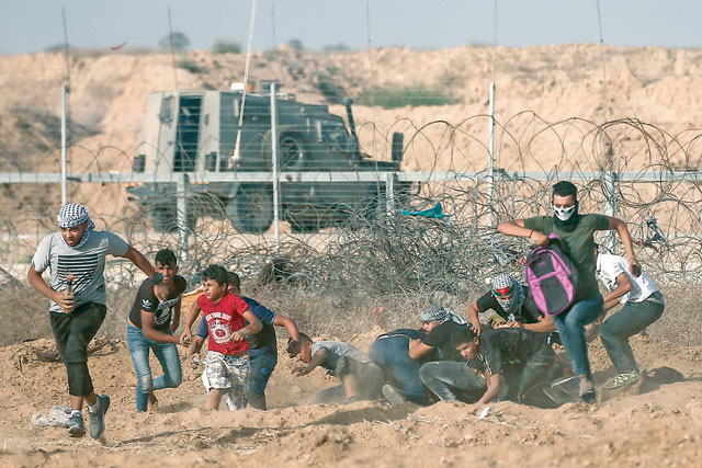 Palestinian demonstrators run away from the fence during protests along the border with Israel, east of Khan Younis, in the southern Gaza Strip on Friday (AFP photo)