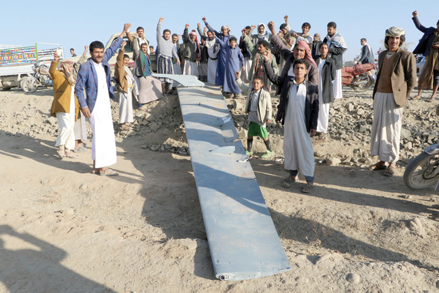 People react as they stand by the wing of a drone the Houthis say they brought down near the northwestern city of Saada, Yemen, on Sunday (Reuters photo)