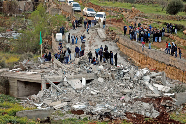 People gather around the house of Palestinian assailant Assam Al Barghouthi after it was demolished by Israeli forces in the village of Kobar near Ramallah, in the Israeli-occupied West Bank, on Thursday (Reuters photo)