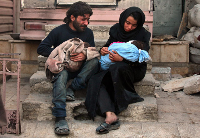 A Syrian man and a woman mourn over the body of one of their children in the rebel-held besieged town of Douma following air strikes on the Eastern Ghouta region on the outskirts of the capital Damascus on January 8 (AFP photo)