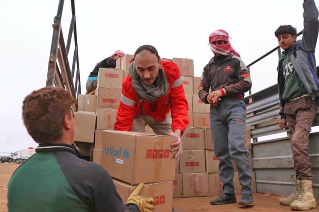 Workers of the Syrian Arab Red Cross unload humanitarian aids in the Rukban desert camp for displaced Syrians along Syria's border with Jordan on Sunday (AFP photo)