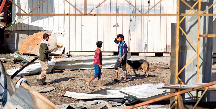 People walk amidst the debris following a reported air strike on a plastic factory in Sanaa's Jeraf district on Wednesday (AFP photo)