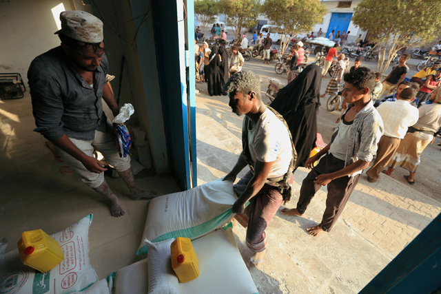 A worker carries a sack of wheat flour at a United Nations aid distribution centre in Hodeida, Yemen, on Tuesday  (Reuters photo)