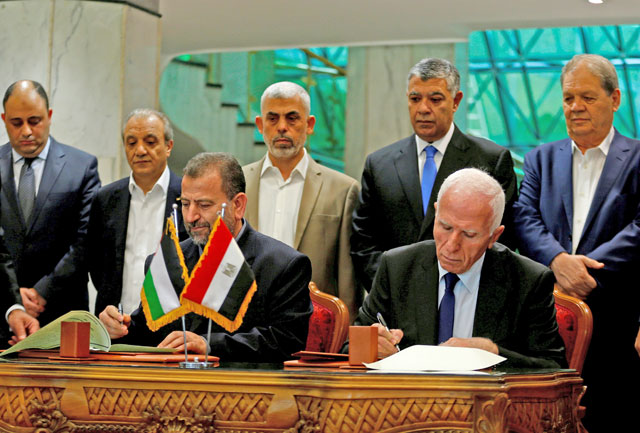 Head of Hamas delegation Saleh Arouri and Fateh leader Azzam Ahmad sign a reconciliation deal in Cairo, Egypt, on Thursday (Reuters photo)