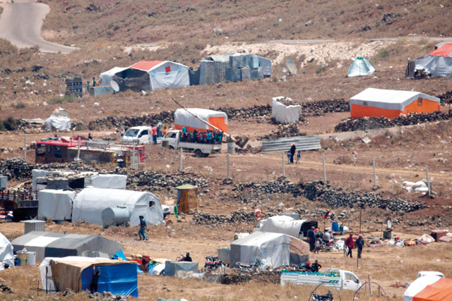 A photo taken on Tuesday from the Israeli-annexed Syrian Golan Heights shows refugees coming to fence border between Syria and Israel by a camp for displaced Syrians near the Syrian village of Burayqah, in the southern province of Quneitra (AFP photo)