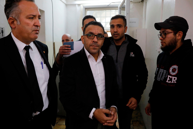Adnan Gheith (centre), Palestinian governor of Jerusalem, is brought handcuffed to a remand hearing at the Magistrate's Court in Jerusalem on Sunday (AFP photo)