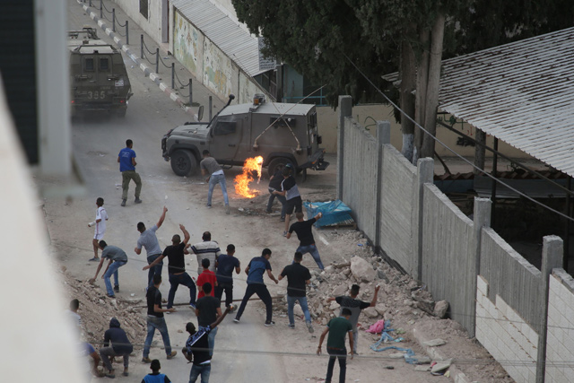Protesters throw stones and molotov cocktails at Israeli forces in the village of Shuwaykah where the man who shot dead two Israelis earlier used to live, in the occupied West Bank, on Sunday (AFP photo)