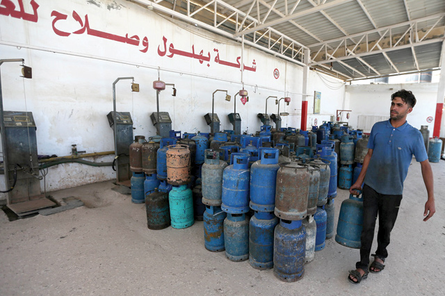 A Palestinian worker carries a cylinder to be filled with cooking gas imported from Egypt in Rafah, southern Gaza Strip, on Monday (Reuters photo)