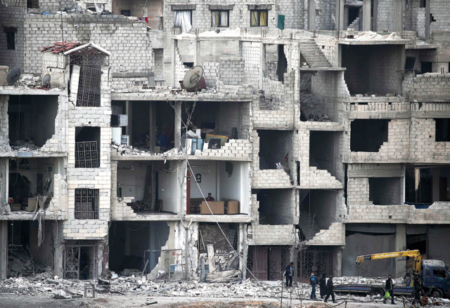 Syrians walk past destroyed buildings in Arbin in the rebel-held enclave of Eastern Ghouta on Sunday. New regime air strikes and heavy clashes shook Syria's rebel enclave of Eastern Ghouta, despite a UN demand for a ceasefire to end one of the most ferocious assaults of Syria's civil war (AFP photo)