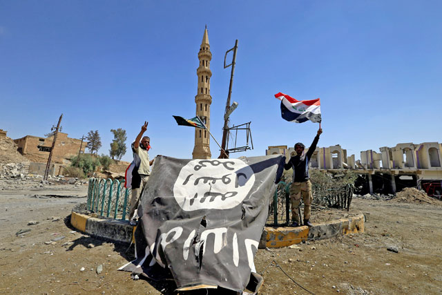 Shiite Popular Mobilisation Forces (PMF) members hold a Daesh flag, which they pulled down, during the war between Iraqi army and PMF against Daesh militants in Tal Afar, Iraq, on August 27, 2017 (Reuters file photo)