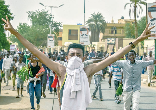 A Sudanese protester covering his face with a jersey flashes the victory gesture while marching with others in a mass demonstration against the country's ruling generals in the capital Khartoum's twin city of Omdurman on Sunday (AFP photo)