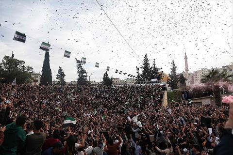 Crowds cheer as flowers and confetti are tossed by army helicopters, during the commemoration of the 10th anniversary of the taking of Idlib from the former president Bashar Al Assad's army by opposition forces in 2015, in Syria's northern city of Idlib on March 28, 2025 (AFP photo)