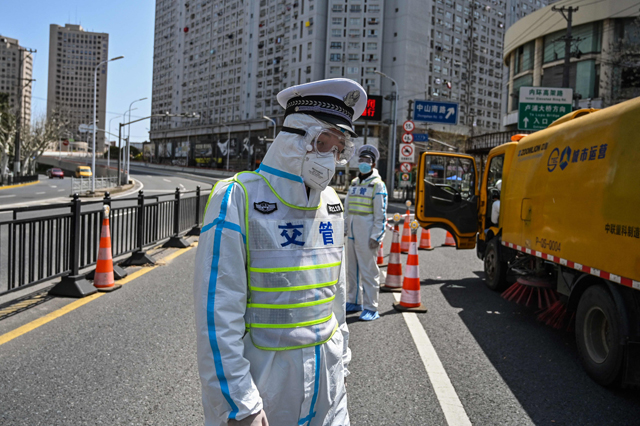 Transit officers, wearing a protective gear, control access to a bridge in the direction of Pudong district in lockdown as a measure against the COVID-19 coronavirus, in Shanghai, on Tuesday (AFP photo)