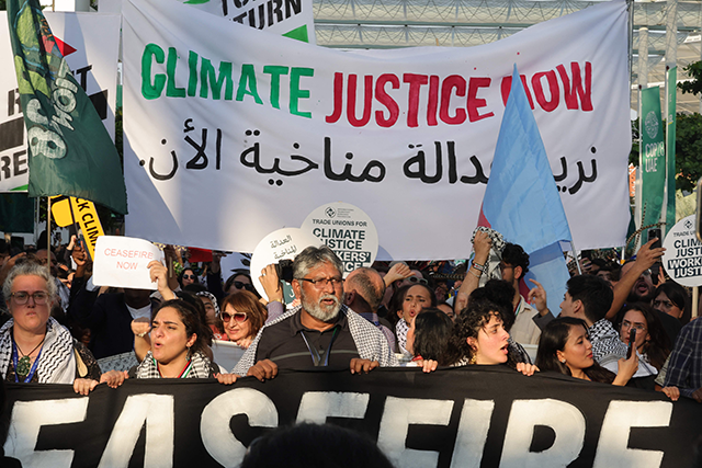 Climate activists raise banners during a joint 'climate justice' and 'ceasefire now' march, demanding an end to the violence in the Gaza Strip, at the United Nations climate summit in Dubai on Saturday (AFP photo)