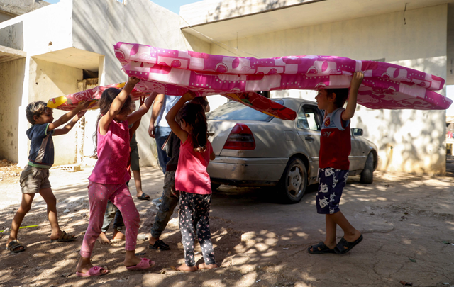 Syrian refugee children displaced from south Lebanon to the northern town of Qornet Akkar carry mattresses distributed by the international NGO INARA, on October 8, 2024 (AFP photo)