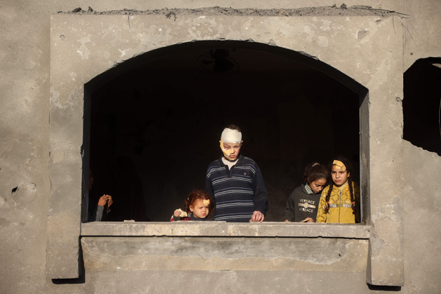 Injured children look on from inside a damaged building at the site of an Israeli strike that targeted the Abu Samra family home in Deir El Balah in the central Gaza Strip on December 22, 2024