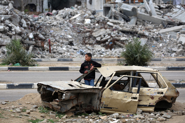 A Palestinian child stands inside a damaged car in front of a destroyed building in the war-devastated Bureij refugee camp in the central Gaza Strip on February 7, 2025 (AFP photo)