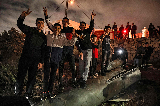 Palestinian youths celebrate as they stand atop a fallen projectile after Iran launched a barrage of missiles at Israel in response to the killings of Lebanese Hizbollah leader Nasrallah and other Iran-backed militants, in Ramallah in the occupied West Bank on October 1, 2024 (AFP photo)