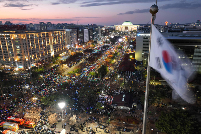 A South Korea flag flutters in the wind as a general view shows people taking part in a protest calling for the ouster of South Korea President Yoon Suk Yeol outside the National Assembly in Seoul on December 7, 2024 (AFP photo)