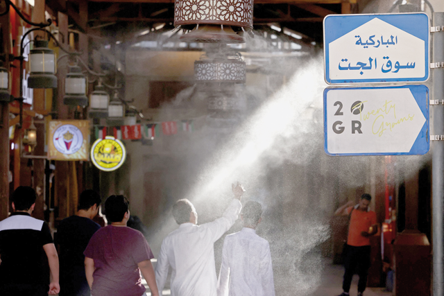 People walk through a mist dispenser as they enter Al Mubarakiya Market amid soaring temperatures in Kuwait City on July 23 (AFP photo)