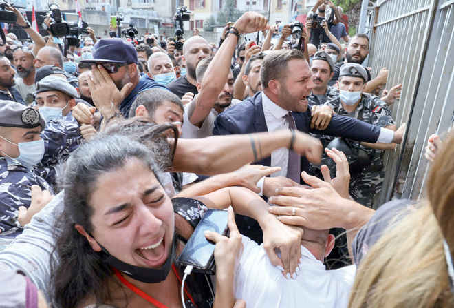 Activists and relatives of victims of the Beirut port explosion scuffle among themselves as Lebanese security members try to interfere during a demonstration on Wednesday outside the capital's Justice Palace, to protest the suspension of the investigation into the August 4, 2020 port explosion (AFP photo)