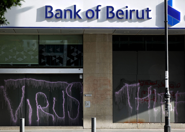 In this file photo taken on May 18, 2020, graffiti reading 'virus' and 'thief' covers the facade of a fortified local branch of the Bank of Beirut in the Lebanese capital (AFP photo)