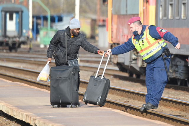 A refugee arriving by train from Ukraine is helped by a Hungarian police officer at the railway station in the Hungarian-Ukrainian border town of Zahony on Tuesday (AFP photo)