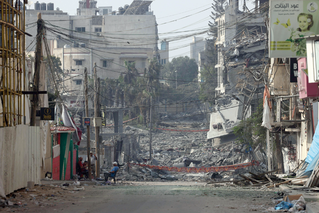 A man sits in front of buildings destroyed by Israeli strikes in Gaza City on Saturday (AFP photo)
