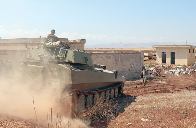 A Syrian government tank drives next to a building near the town of Khan Sheikhun in the southern countryside of the rebel-held Idlib province on August 18  (AFP photo)