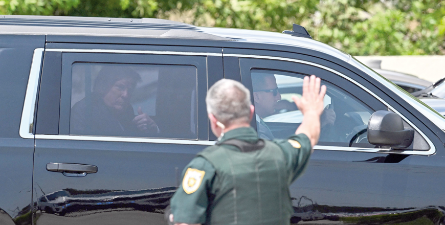 A policeman waves at former US President Donald Trump as he arrives at Palm Beach International Airport in West Palm Beach, Florida, on April 3, 2023 (AFP photo)