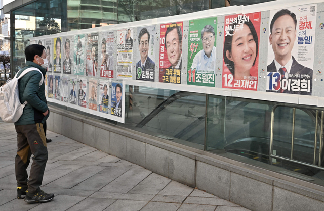 This photo taken on Sunday shows a man looking at posters of South Korea's presidential candidates (top row) in Seoul ahead of the March 9 presidential election (AFP photo)