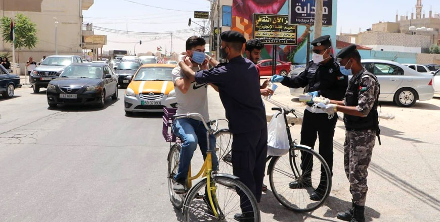 Public Security Directorate personnel hand out masks and gloves to two cyclists in this recent photo (Photo courtesy of Public Security Directorate Facebook page)