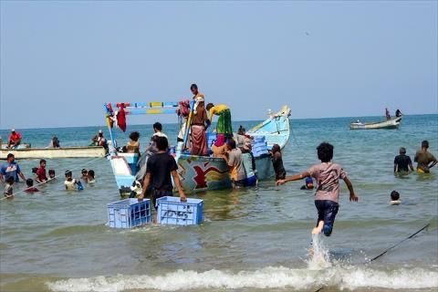 A child plays as fishermen sit in boats near the Red Sea shore in the Khokha district on the southern edge of the Yemen's western Red Sea city of Hodeida on May 16, 2025 (AFP photo)
