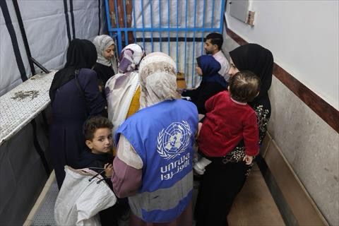 A staff member helps Palestinian families awaiting care at the UNRWA-run clinic at al-Shati refugee camp west of Gaza City on April 28, 2025 (AFP photo)