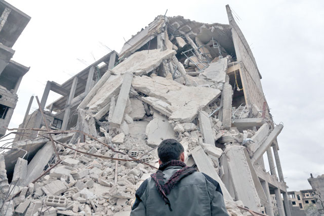 This photo shows a Syrian youth standing next to the rubble of a destroyed building in Haza in the besieged Eastern Ghouta region on the outskirts of the capital Damascus on Monday (AFP photo)