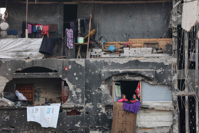 Displaced Palestinian girls look out a damaged house where they took shelter in Beit Lahia in the northern Gaza Strip, ahead of the iftar fast-breaking meal during the Muslim holy month of Ramadan on March 9, 2025 (AFP photo)