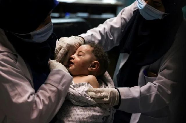 A nurse holds a five-month-old Palestinian baby, pulled alive from the rubble of his home where his mother and nine other extended family members were killed in an Israeli air strike (AFP photo)