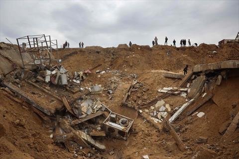 Palestinians inspect building rubble in a crater following an Israeli strike on a fishing harbour in Deir El Balah in the central Gaza Strip on March 22, 2025 (AFP photo)
