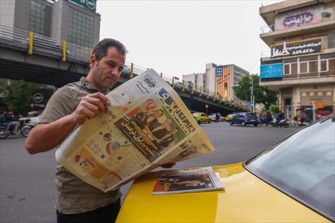 An Iranian man reads a newspaper on a Tehran street on April 12, 2025, with the front page featuring the Iran-US talks on the Iranian nuclear programme set to begin in Oman on the same day (AFP photo)