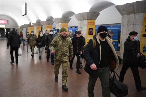 People, some carrying bags and suitcases, walk in a metro station in Kyiv early on February 24, 2022. Air raid sirens rang out in downtown Kyiv on Thursday as cities across Ukraine were hit with what Ukrainian officials said were Russian missile strikes and artillery