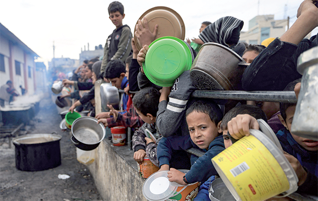 Palestinians wait to collect food at a donation point in a refugee camp in Rafah in the southern Gaza Strip on Saturday (AFP photo)