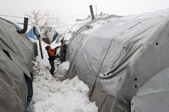 A boy clears snow from one of the tents at a camp for the internally displaced near the city of Jisr Al Shughur in Syria's northwestern province of Idlib on January 26 (AFP photo)